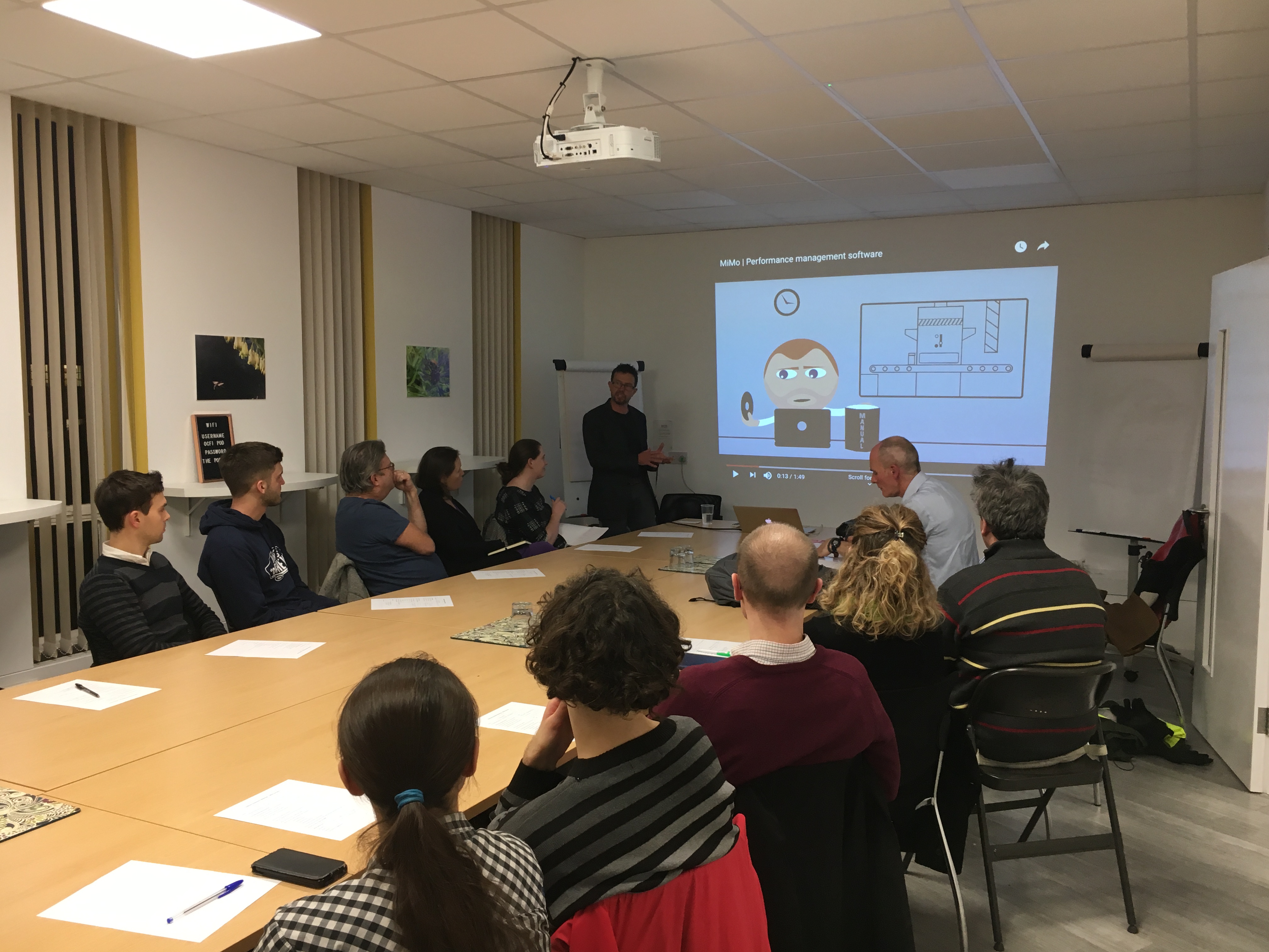 man presenting to a room of people around a boardroom table